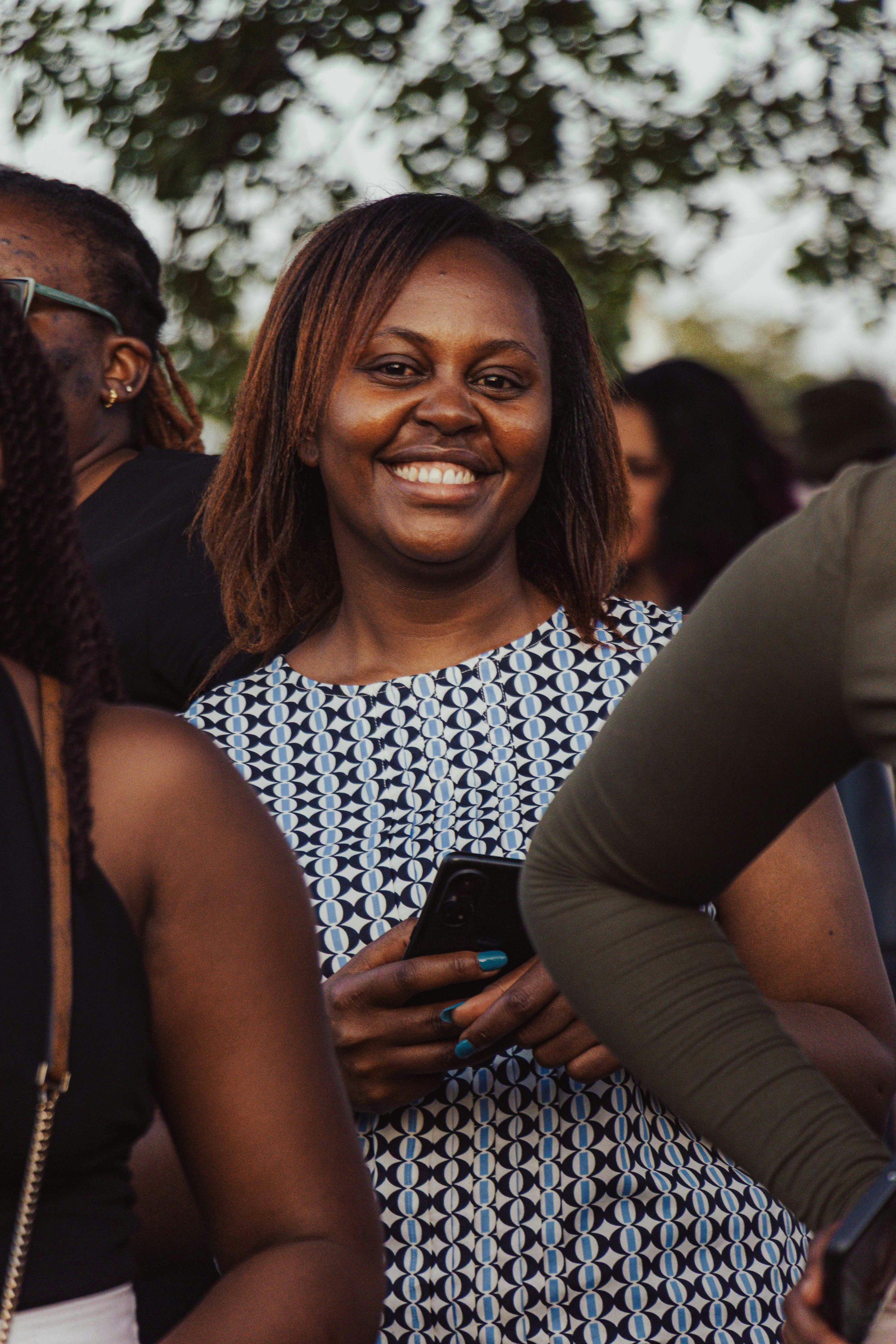A woman smiles at her phone outdoors after a warm text from her church